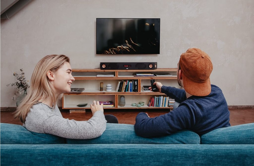 Hombre y mujer en el sofá frente al televisor con una barra de sonido Teufel