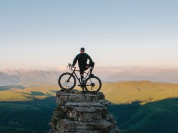 Mann mit Fahrrad auf Berg