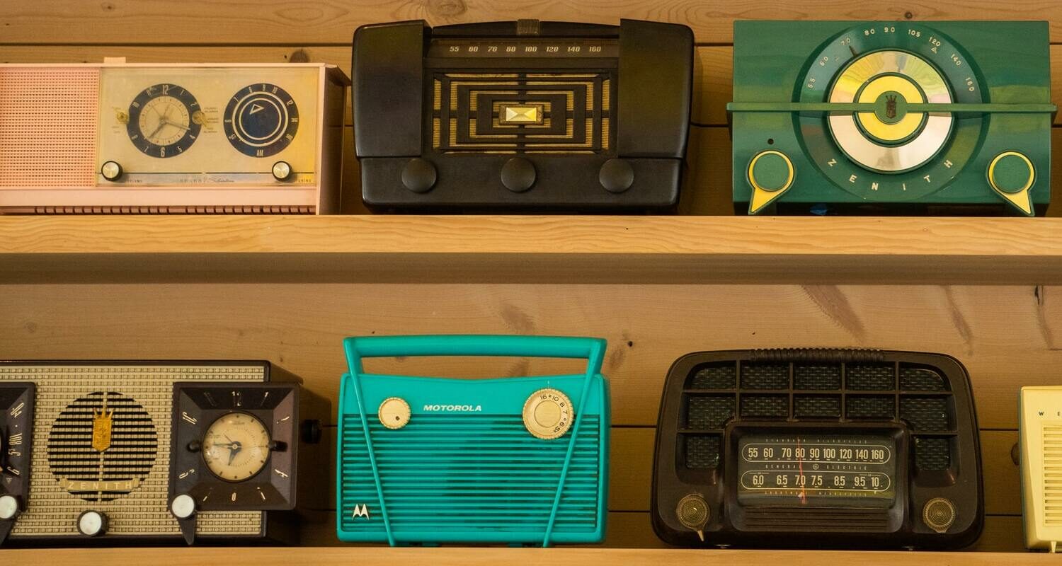 Verschiedene Radio-Modelle auf einem Holzregal.