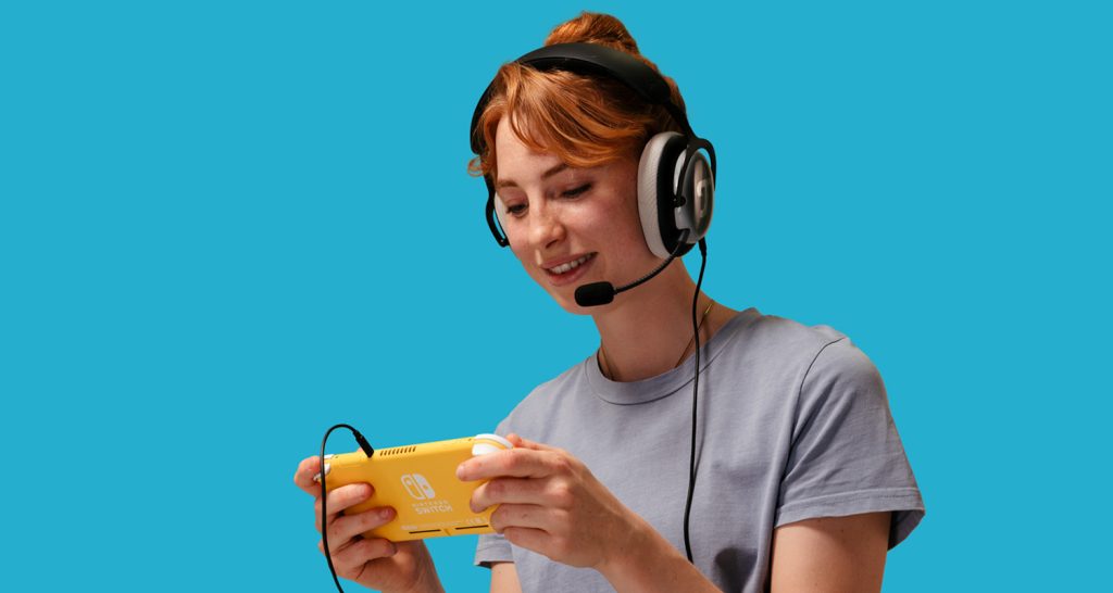 Una mujer lleva los auriculares ZOLA de Teufel, que están conectados a una Nintendo Switch Lite mediante un cable