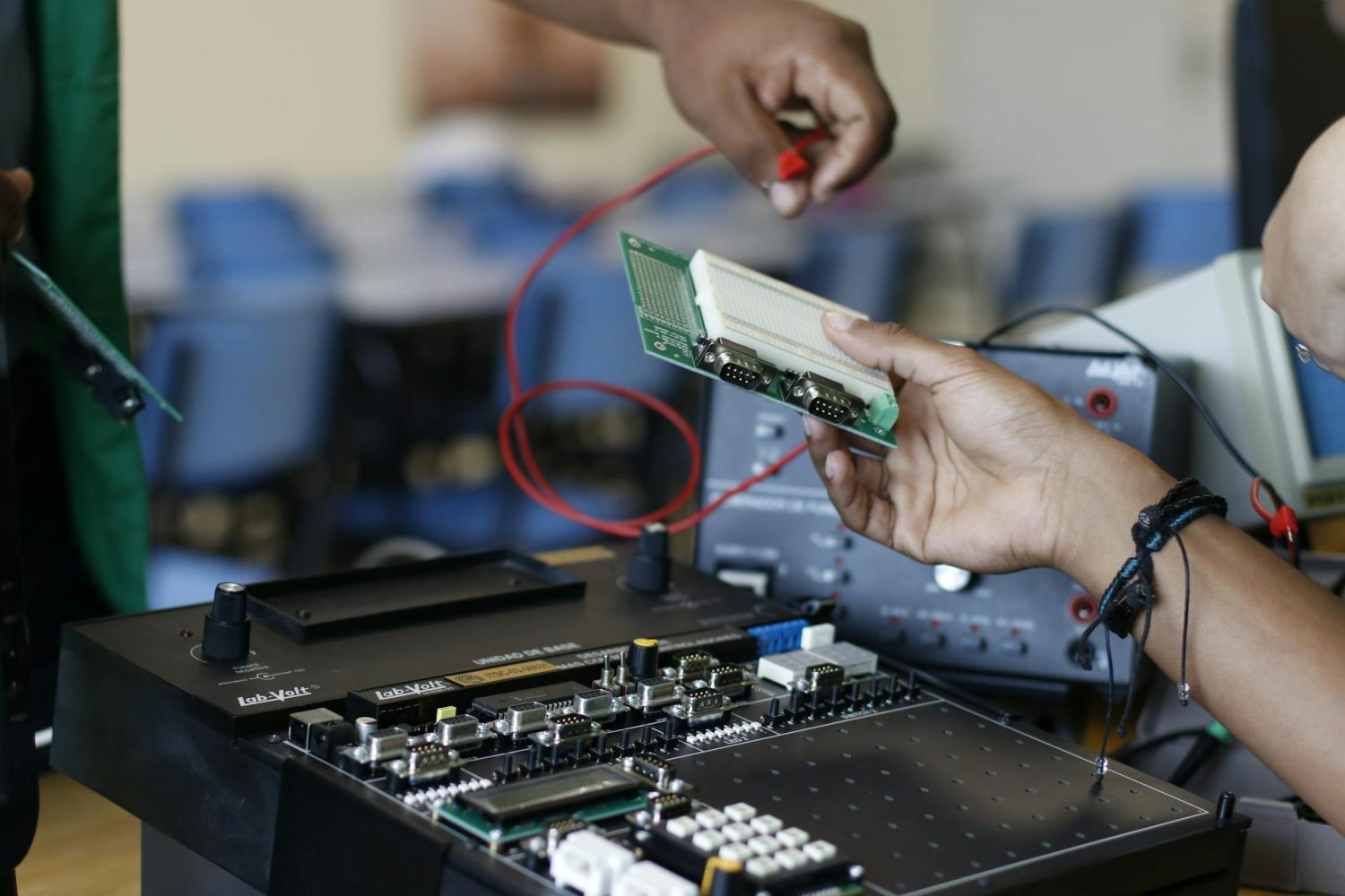 Dos personas trabajando en un circuito electrónico con cables