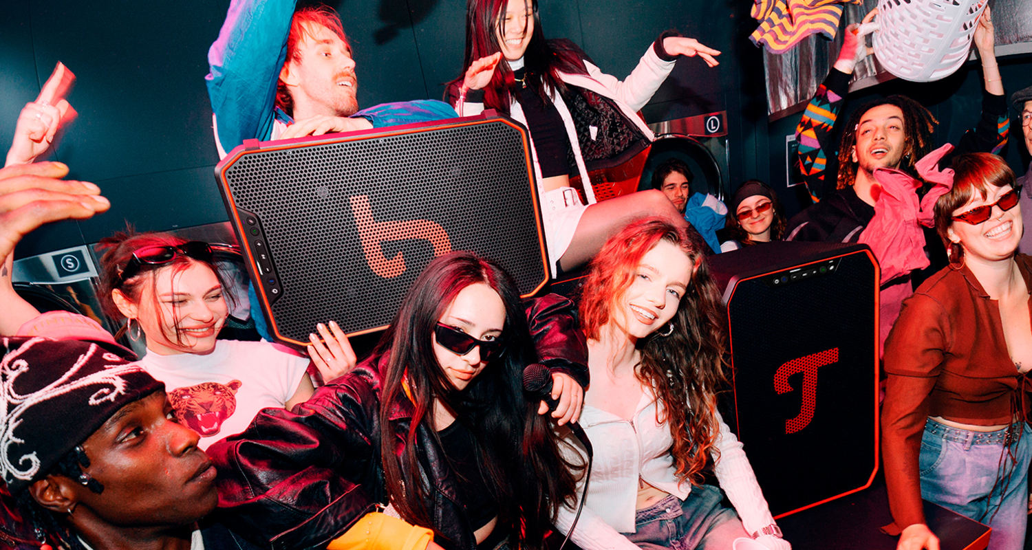 Gruppe junger Menschen feiert mit zwei ROCKSTER NEO Lautsprechern von Teufel