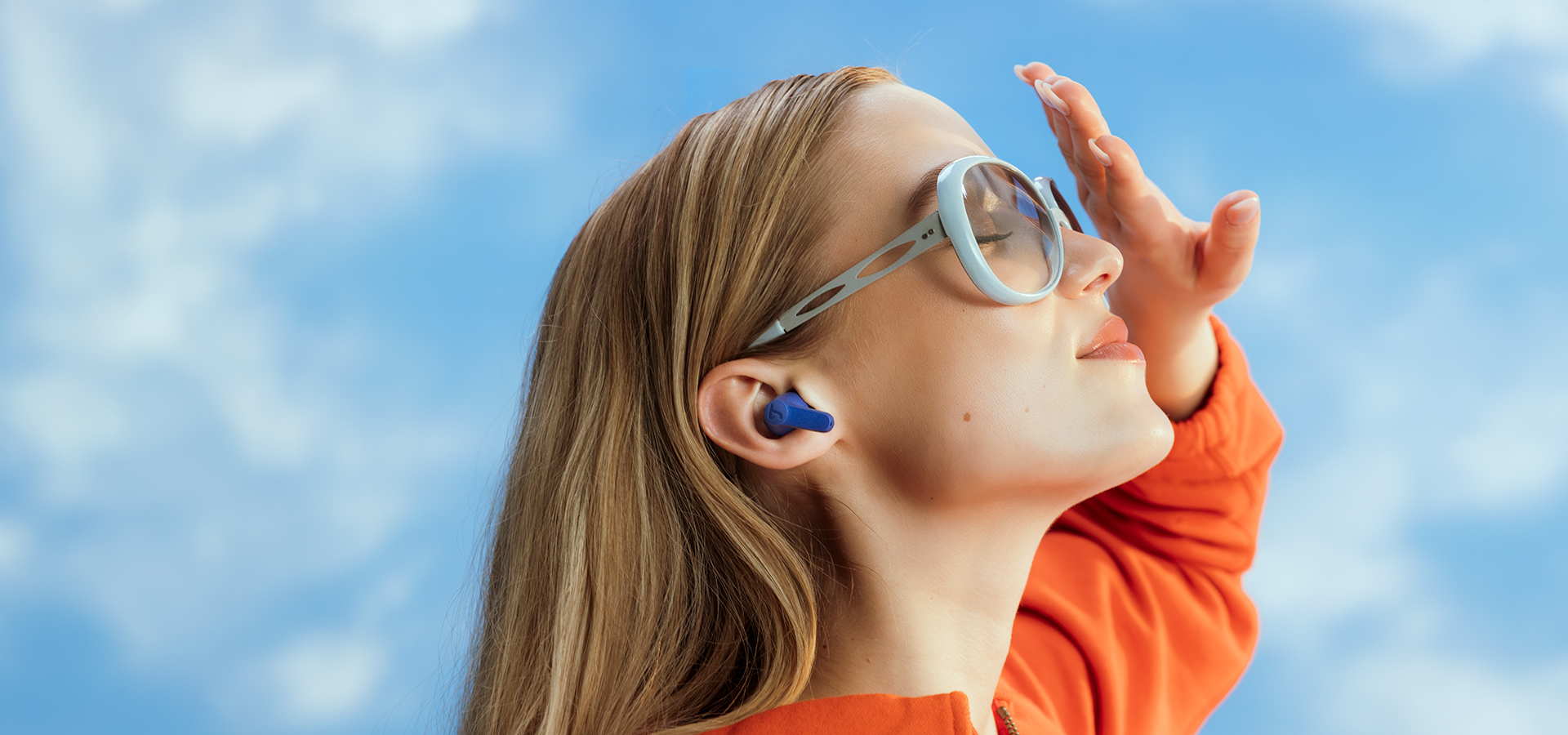 Kind mit Kopfhörern und Sonnenbrille genießt die erste Frühlingsonne